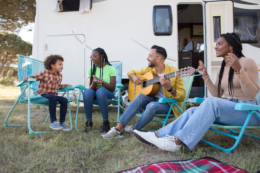 A diverse family spending quality time playing guitar by a caravan in Portugal.